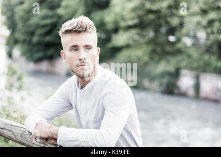 Blondish, blue eyed young man by river smiling Stock Photo