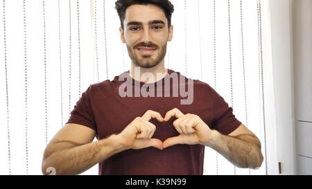 Handsome young man making heart sign with hands Stock Photo