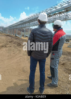 Two engineers discuss the construction of a trestle for pipes in an oil port Stock Photo