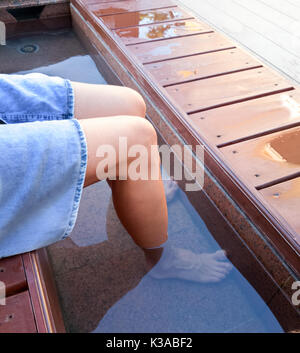 woman hovers her feet in the open city onsen at the bus stop Yonago,Japan Stock Photo
