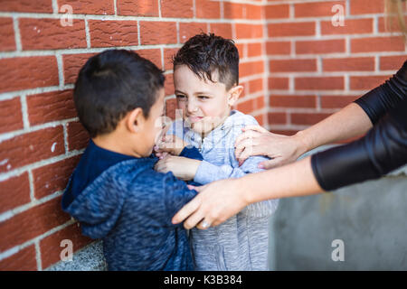Teacher Stopping Two Boys Fighting In Playground Stock Photo