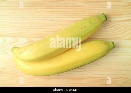 Top View of a Pair of Bright Yellow Ripe Bananas Isolated on Wooden Background Stock Photo