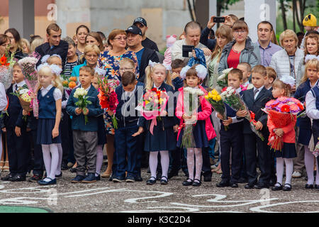 NOVOKUZNETSK, KEMEROVO REGION, RUSSIA - SEP, 1, 2017: Meeting with the first-grade pupils and teacher at schoolyard. The day of knowledge in Russia. Stock Photo