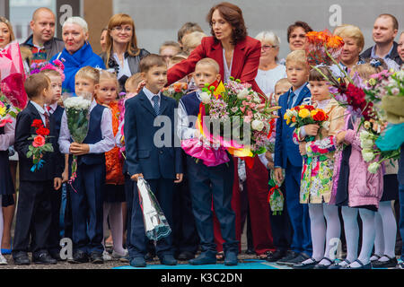 NOVOKUZNETSK, KEMEROVO REGION, RUSSIA - SEP, 1, 2017: Meeting with the first-grade pupils and teacher at schoolyard. The day of knowledge in Russia. Stock Photo