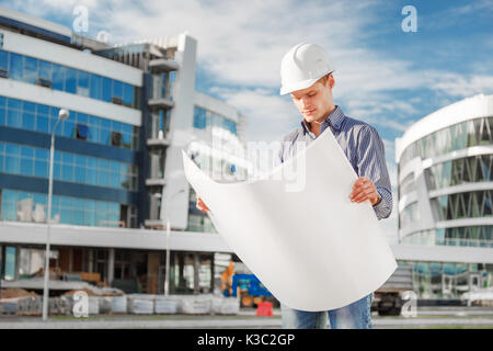 Architect in helmet with blueprints at work Stock Photo