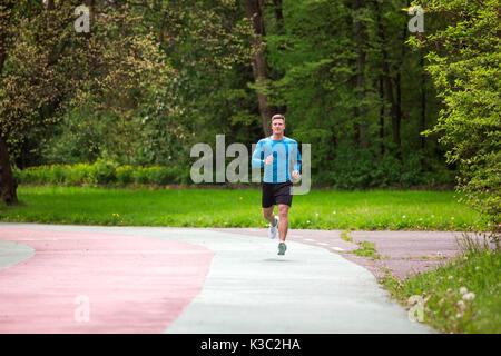 A photo of young, muscular man jogging on the racetrack. Stock Photo