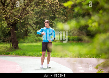 A photo of young, well-built man looking at the wristwatch. Stock Photo