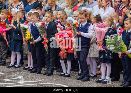 NOVOKUZNETSK, KEMEROVO REGION, RUSSIA - SEP, 1, 2017: Meeting with the first-grade pupils and teacher at schoolyard. The day of knowledge in Russia. Stock Photo