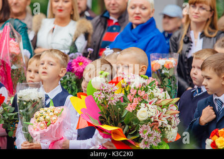 NOVOKUZNETSK, KEMEROVO REGION, RUSSIA - SEP, 1, 2017: Meeting with the first-grade pupils and teacher at schoolyard. The day of knowledge in Russia. Stock Photo