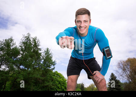 A photo of young, muscular man in sports wear pointing at the camera and smiling. Stock Photo