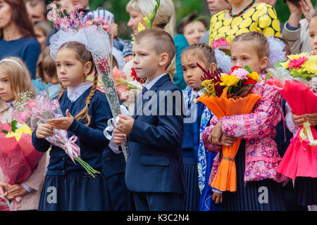 NOVOKUZNETSK, KEMEROVO REGION, RUSSIA - SEP, 1, 2017: Meeting with the first-grade pupils and teacher at schoolyard. The day of knowledge in Russia. Stock Photo