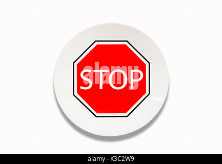 Conceptual idea. white plate with clock in the interior. Knife and fork. On the background of the plate the sign is STOP. after 8 pm. Stock Photo