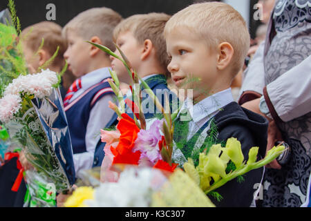 NOVOKUZNETSK, KEMEROVO REGION, RUSSIA - SEP, 1, 2017: Meeting with the first-grade pupils and teacher at schoolyard. The day of knowledge in Russia. Stock Photo