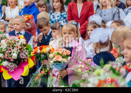 NOVOKUZNETSK, KEMEROVO REGION, RUSSIA - SEP, 1, 2017: Meeting with the first-grade pupils and teacher at schoolyard. The day of knowledge in Russia. Stock Photo