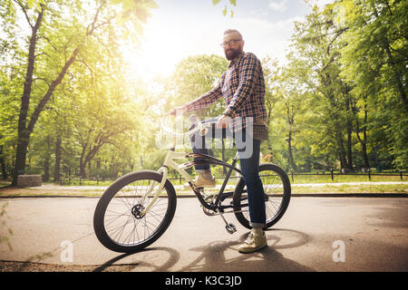 Full portrait of happy young man standing with bike at park Stock Photo