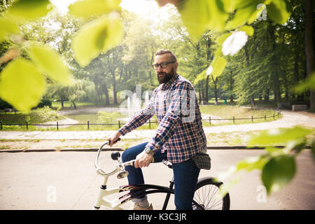 Portrait of young confident man sitting on bike at park Stock Photo