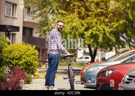 Portrait of young hipster man standing on pavement with bike Stock Photo