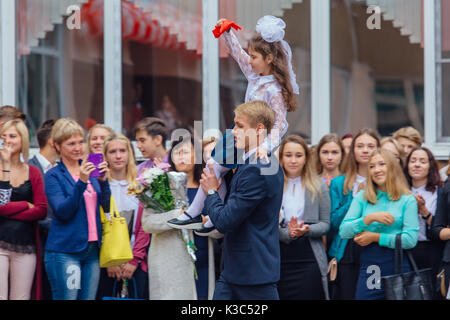 NOVOKUZNETSK, KEMEROVO REGION, RUSSIA - SEP, 1, 2017: Meeting with the first-grade pupils and teacher at schoolyard. The day of knowledge in Russia. Stock Photo