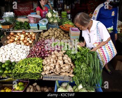 MARIKINA CITY, PHILIPPINES - AUGUST 28, 2017: Customers buy fresh vegetables from a vegetable store at a public market. Stock Photo