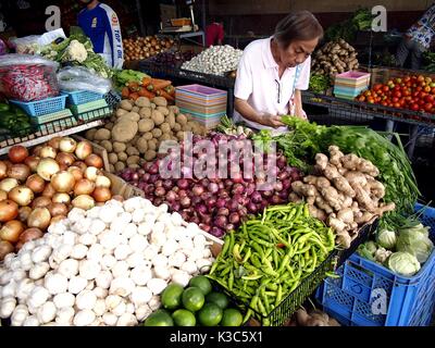 MARIKINA CITY, PHILIPPINES - AUGUST 28, 2017: Customers buy fresh vegetables from a vegetable store at a public market. Stock Photo