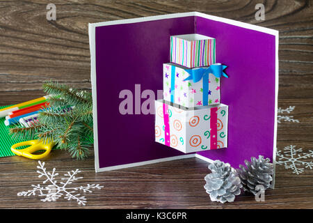 A child makes a birthday card with Christmas presents. Made by own hands. Children's art project, craft for children. Craft for children. Copy space. Stock Photo