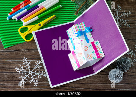 A child makes a birthday card with Christmas presents. Made by own hands. Children's art project, craft for children. Craft for children. Stock Photo