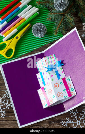 A child makes a birthday card with Christmas presents. Made by own hands. Children's art project, craft for children. Craft for children. Stock Photo