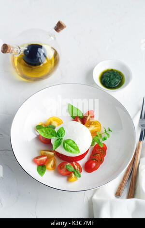 Caprese salad with ripe cherry tomatoes and mozzarella cheese with fresh basil leaves isolated on the white background. Top view. Stock Photo