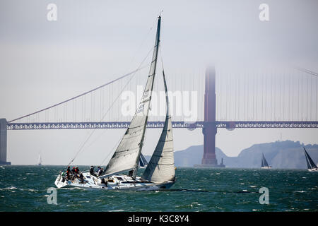 Closeup of white sailboat sailing in strong wind toward Golden Gate Bridge Stock Photo