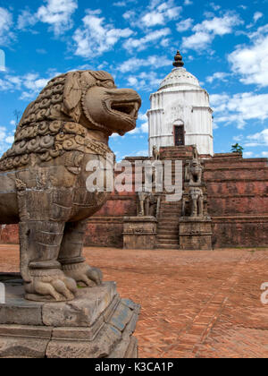 Ancient stone lions and the large white Fasidega Temple dedicated to Shiva  in Bhaktapur, on a background Blue Sky and wight clouds, Nepal Stock Photo