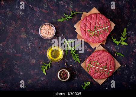 Fresh raw homemade minced beef steak burger with spices on black background Stock Photo