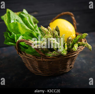 Fresh asparagus in basket on dark  background. Stock Photo