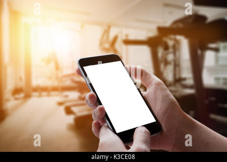 A man hand holding empty screen of smart phone device in Gym. Stock Photo