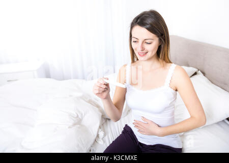 Young woman in bedroom at home wearing in white check pregnant test Stock Photo