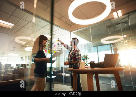 Young man and woman working together in office. Creative professionals working on new project. Stock Photo