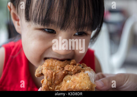Asian Chinese mother and daughter eating fried chicken at indoor restaurant Stock Photo