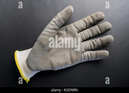 Isolated worn out working gloves against a black surface Stock Photo