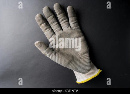 Isolated worn out working gloves against a black surface Stock Photo