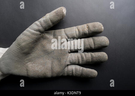 Isolated worn out working gloves against a black surface Stock Photo