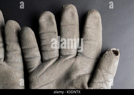 Isolated worn out working gloves against a black surface Stock Photo