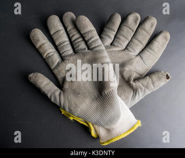 Isolated worn out working gloves against a black surface Stock Photo