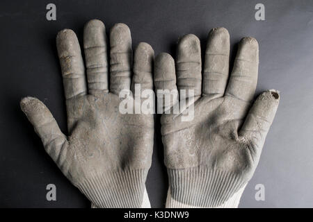 Isolated worn out working gloves against a black surface Stock Photo