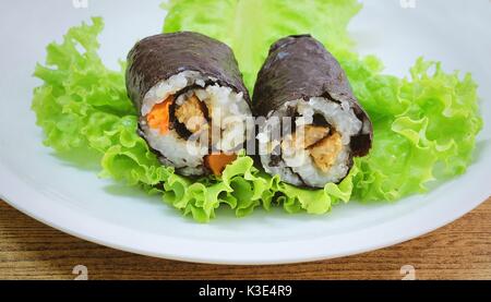 Japanese Cuisine, Traditional Vagetarian Japanese Rice Maki Sushi Roll Stuff with Tofu and Carrot Wrapped in Nori Seaweed Served on Green Oak. Stock Photo