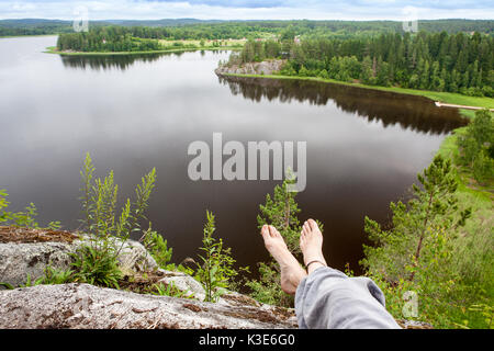 the girl swung his legs off the mountains and enjoying magnificent views. Freedom concept. Stock Photo