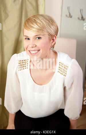 Young smiling blonde woman with short hair in silk blouse. Stock Photo