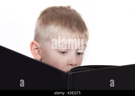 Smart looking boy engaged with reading a big book Stock Photo