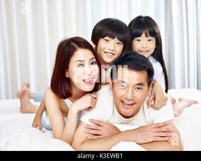 happy asian family with two children having fun in bed at home. Stock Photo