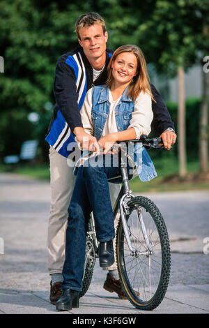 Young couple sits together on a mountain bike Stock Photo
