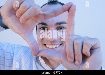 Man forms a rectangle with his hands and looks through Stock Photo