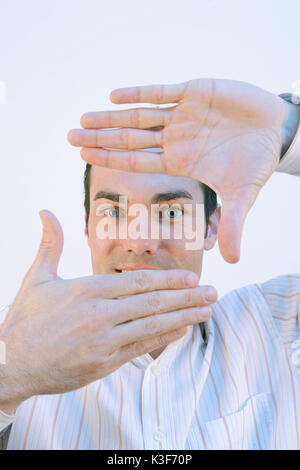 Man forms a rectangle with his hands and looks through Stock Photo